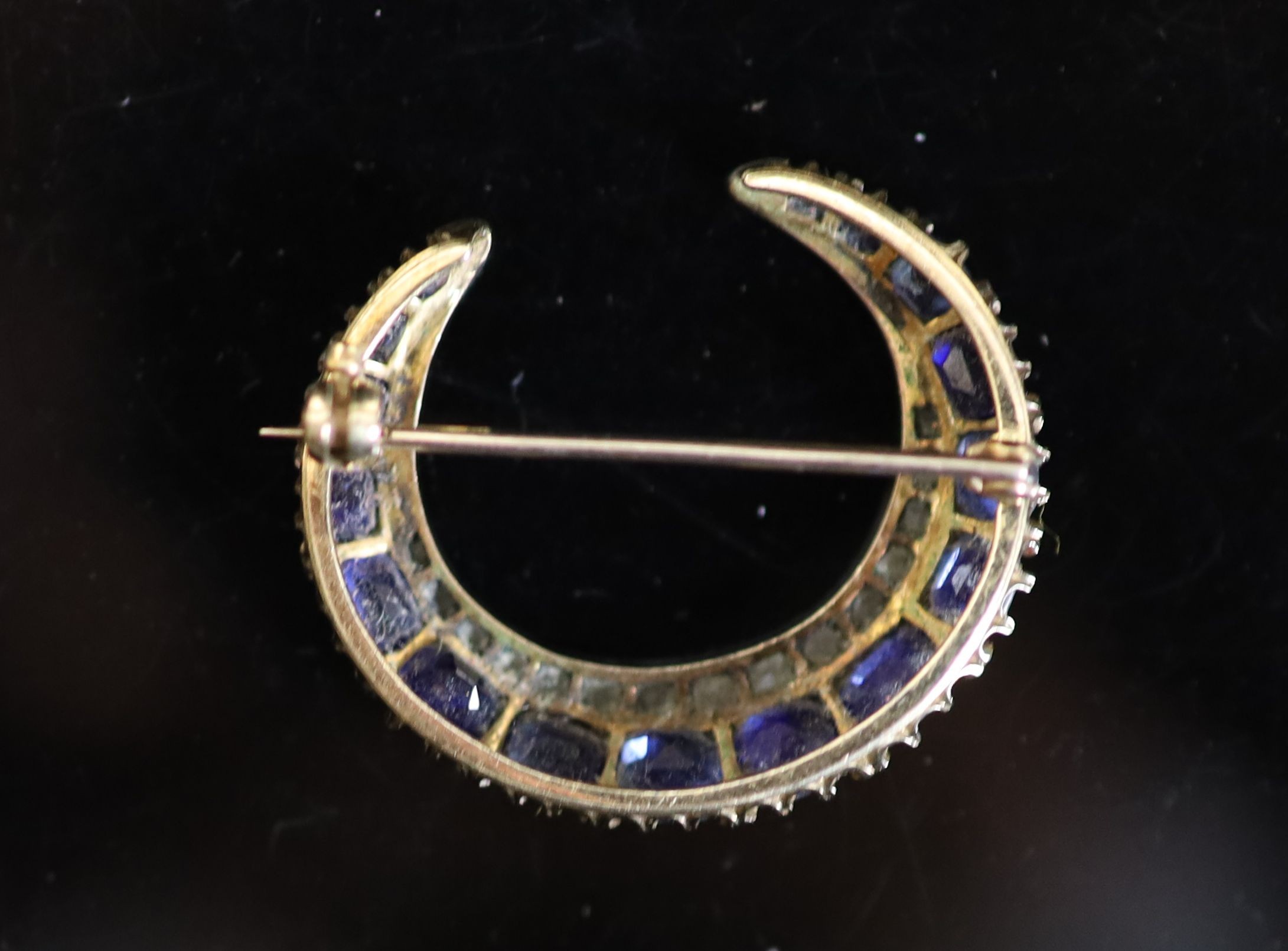 An early 20th century gold, graduated sapphire and rose cut diamond set crescent brooch